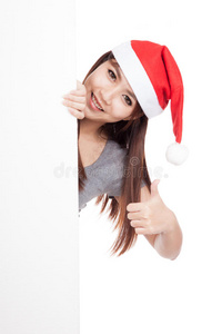 亚洲女孩戴着圣诞帽从一个空白的标志后面偷看