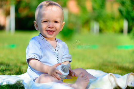 可爱的小男孩坐在绿色的草地上