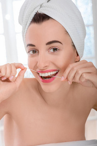 用牙线清洁牙齿的妇女