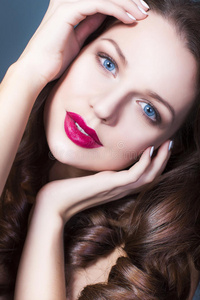 黑发女人，有创意的化妆紫罗兰色眼影丰满的红唇，蓝色的眼睛和卷发，手放在脸上