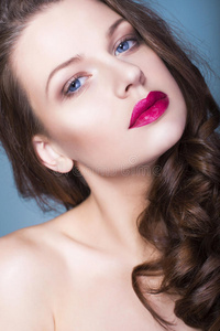 黑发女人，有创意的化妆紫罗兰色眼影丰满的红唇，蓝色的眼睛和卷发，手放在脸上