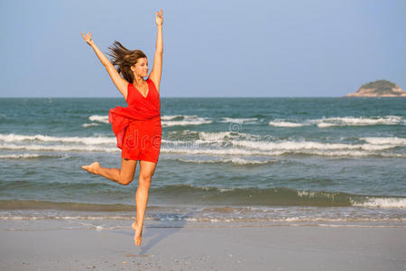 年轻的红发女孩在海滩上跳跃