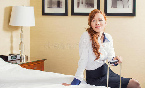 坐在酒店房间的床上快乐的年轻女商人
