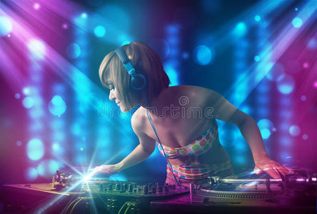dj女孩在蓝色和紫色灯光的俱乐部里混合音乐