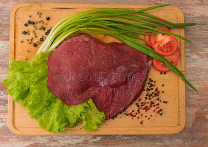 生牛肉和蔬菜放在木盘上。