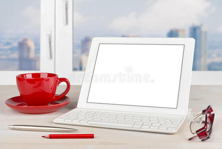 办公桌上有键盘和红色杯子的平板电脑