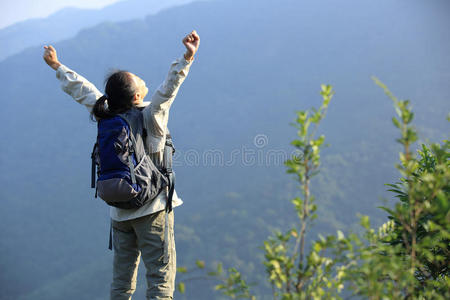 欢呼雀跃的女徒步旅行者在山顶张开双臂