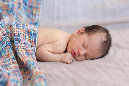 新生婴儿在灰色织物背景上，覆盖着格子花纹