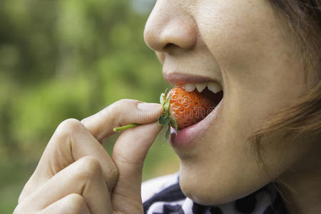 年轻漂亮的女人在吃新鲜草莓