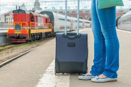 手提箱和女性只脚在一列火车在车站等待