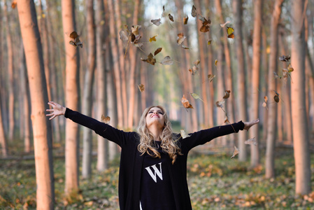 幸福的女人玩秋天离开在森林