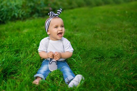 一个小婴儿在牛仔衣服坐在草地上
