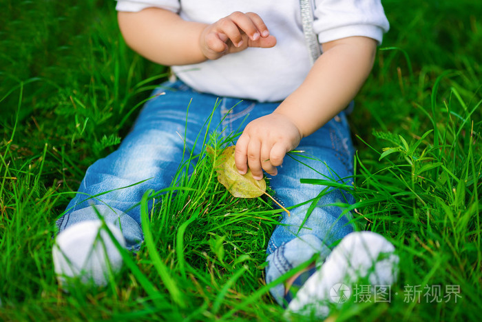 牛仔裤在绿色的草地上一个人类婴儿的双腿