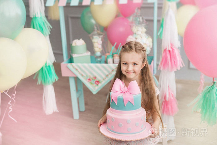 小女孩在一个装饰的房间里举行一个大蛋糕