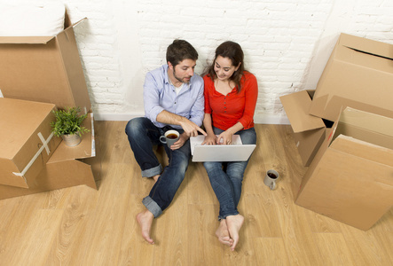 夫妻坐在新房子里，选择家具与电脑笔记本移动的地板上