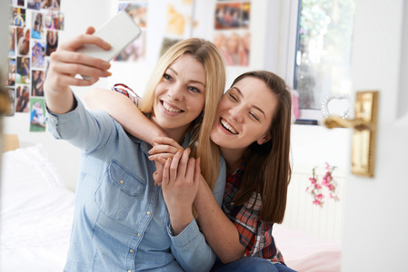 两个十几岁的女孩在家中卧室采取自拍照
