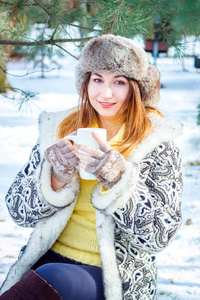 年轻女子冬季肖像。浅景深。微笑的女士拿着一杯茶