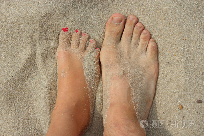 父亲和他十几岁的女儿在沙滩上的脚