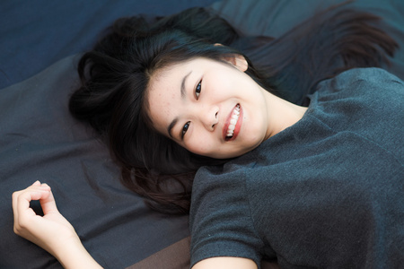 时尚的美丽年轻的亚洲女人躺在床上的照片