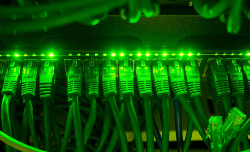 绿色网络电缆连接到交换机在黑暗中发光的特写