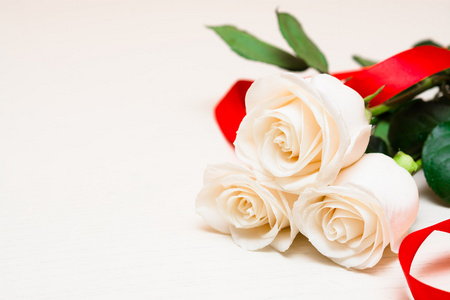 白色玫瑰，红色丝带在轻木背景上。 妇女