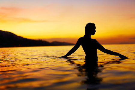 健康的生活方式健康。 享受海上日落的女人。 夏季假期