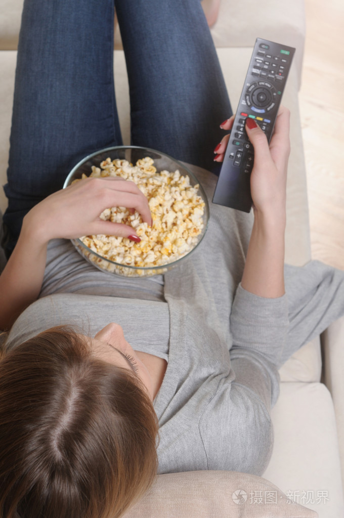 年轻女人花一个轻松的周末在家看电视