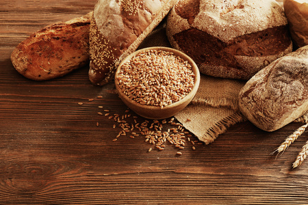 新鲜的烤面包和一碗小麦籽粒的木制的背景