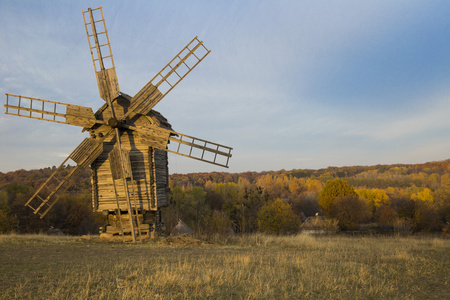 秋在天空风车古老的风车在日落森林附近的田野照片