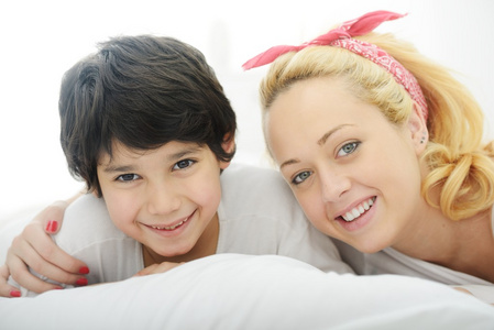 快乐年轻母亲和她的儿子在床上