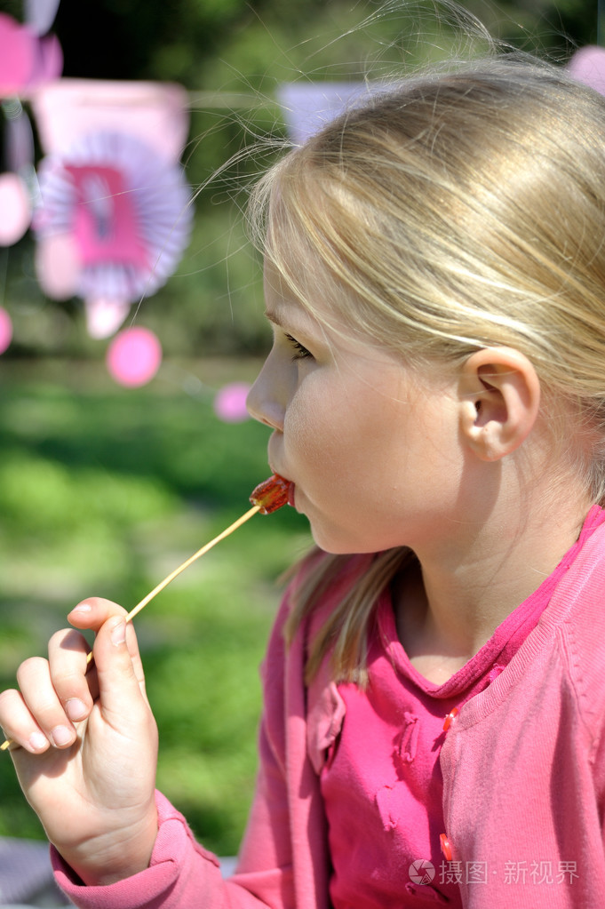 吃棒棒糖的可爱的金发小孩女孩