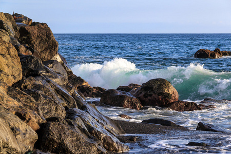 海洋在日落时在海边岩石上