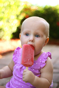 可爱的小宝贝女孩吃冷冻的水果冰棒