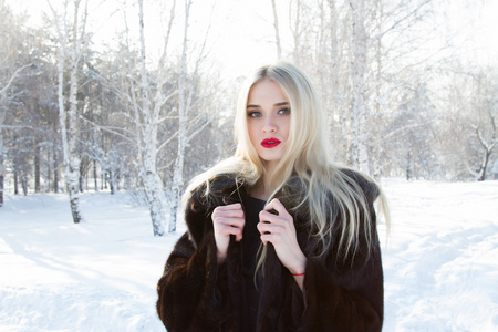 年轻的女孩，在白雪覆盖的森林背景一件貂皮大衣