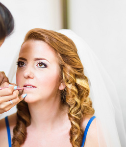 年轻漂亮的新娘应用婚礼化妆的化妆师