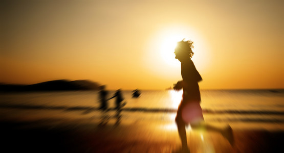 在日落时在海滩上慢跑的男人