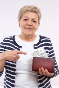 快乐的高级女性显示美元货币在钱包里，在年老时的财务安全概念