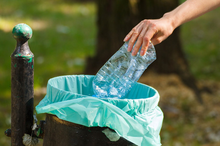 女人把塑料瓶扔进回收箱，手乱抛垃圾的环境