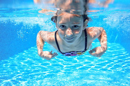 儿童游泳在游泳池水下，快乐积极的女孩已下水，孩子运动家庭度假的乐趣