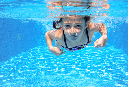 儿童游泳在游泳池水下，快乐积极的女孩已下水，孩子运动家庭度假的乐趣