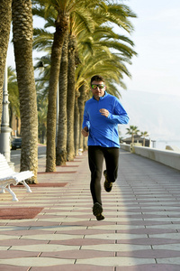 体育人沿着海滩棕榈树大道在早上慢跑训练会话中运行