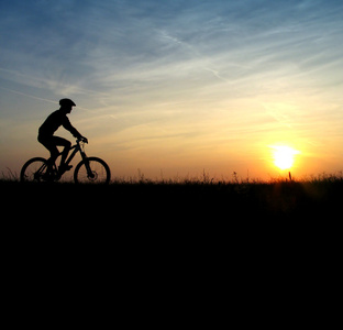 在日出山骑自行车的人剪影