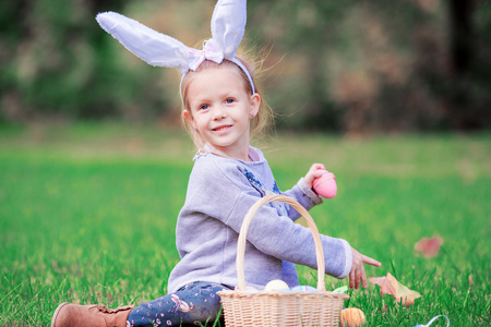 可爱的小女孩，穿着与一篮子的复活节兔子耳朵鸡蛋春日户外