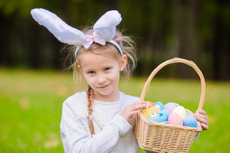 可爱的小女孩，穿着与一篮子的复活节兔子耳朵鸡蛋春日户外