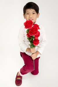 小亚洲男孩在老式西装与红玫瑰