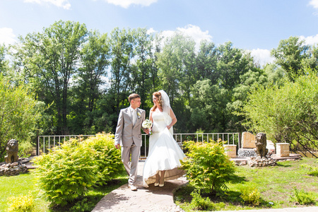 新娘和新郎在婚礼当天到户外散步在春天性质。新婚夫妇，祝新婚快乐女人和男人拥抱绿色的公园里。爱婚礼情侣户外