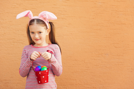 可爱的小女孩戴着兔子耳朵，拿着水桶