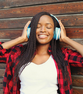 美丽的微笑非洲女人，戴着耳机享受听