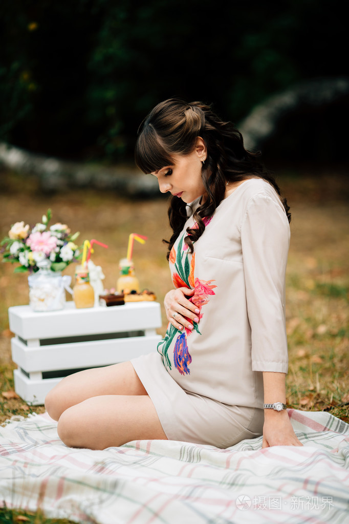 美丽的孕妇坐在肚子上,看上去很可爱.