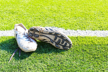 在绿色草地上的老足球鞋。